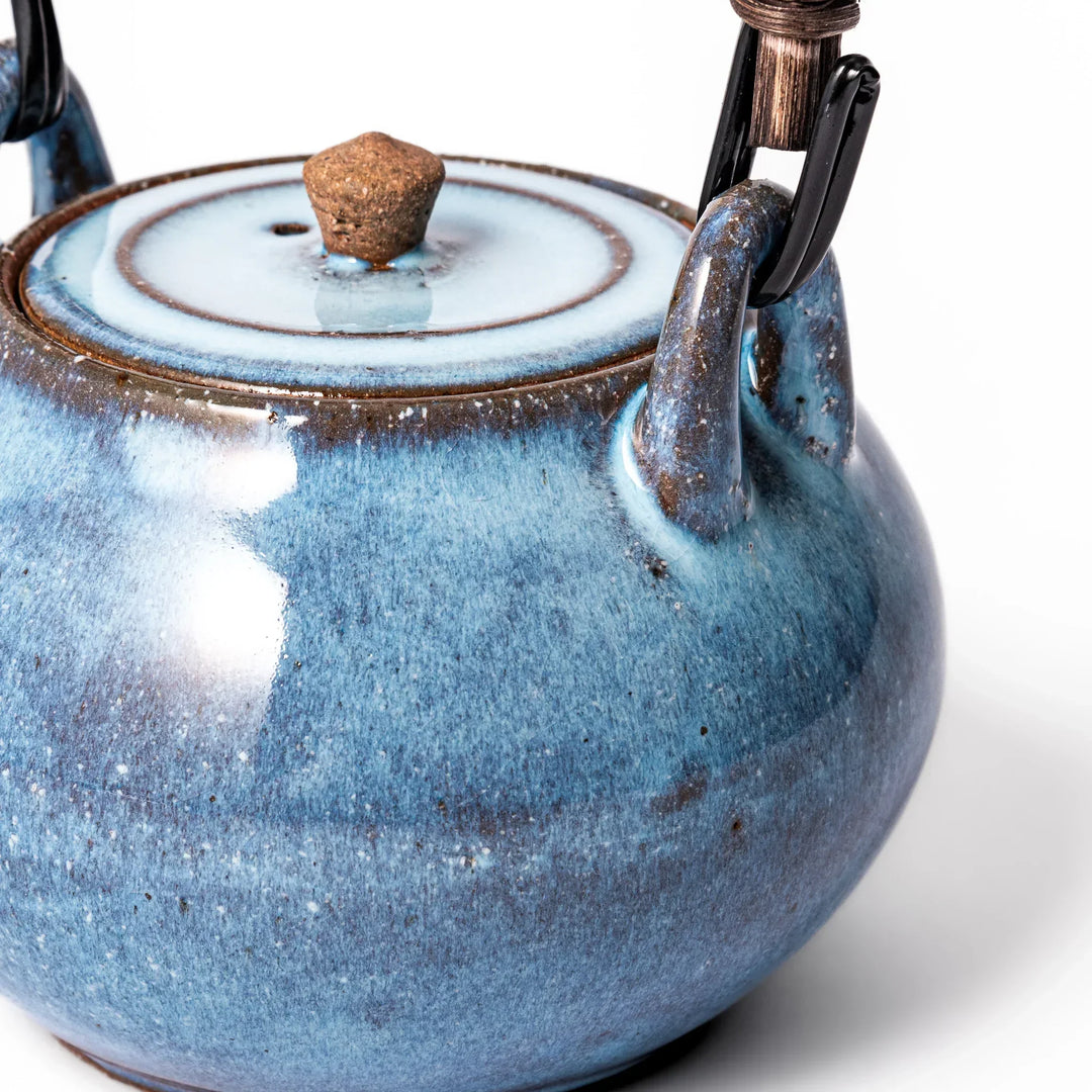 Terracotta blue ceramic teapot with rustic brown rim and metal handle, handcrafted in Japan for daily tea service.