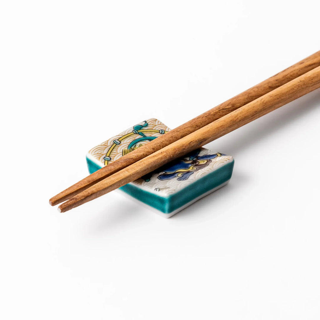 Japanese porcelain chopstick rest featuring the Thunder God design with blue figure and gold wave pattern background.