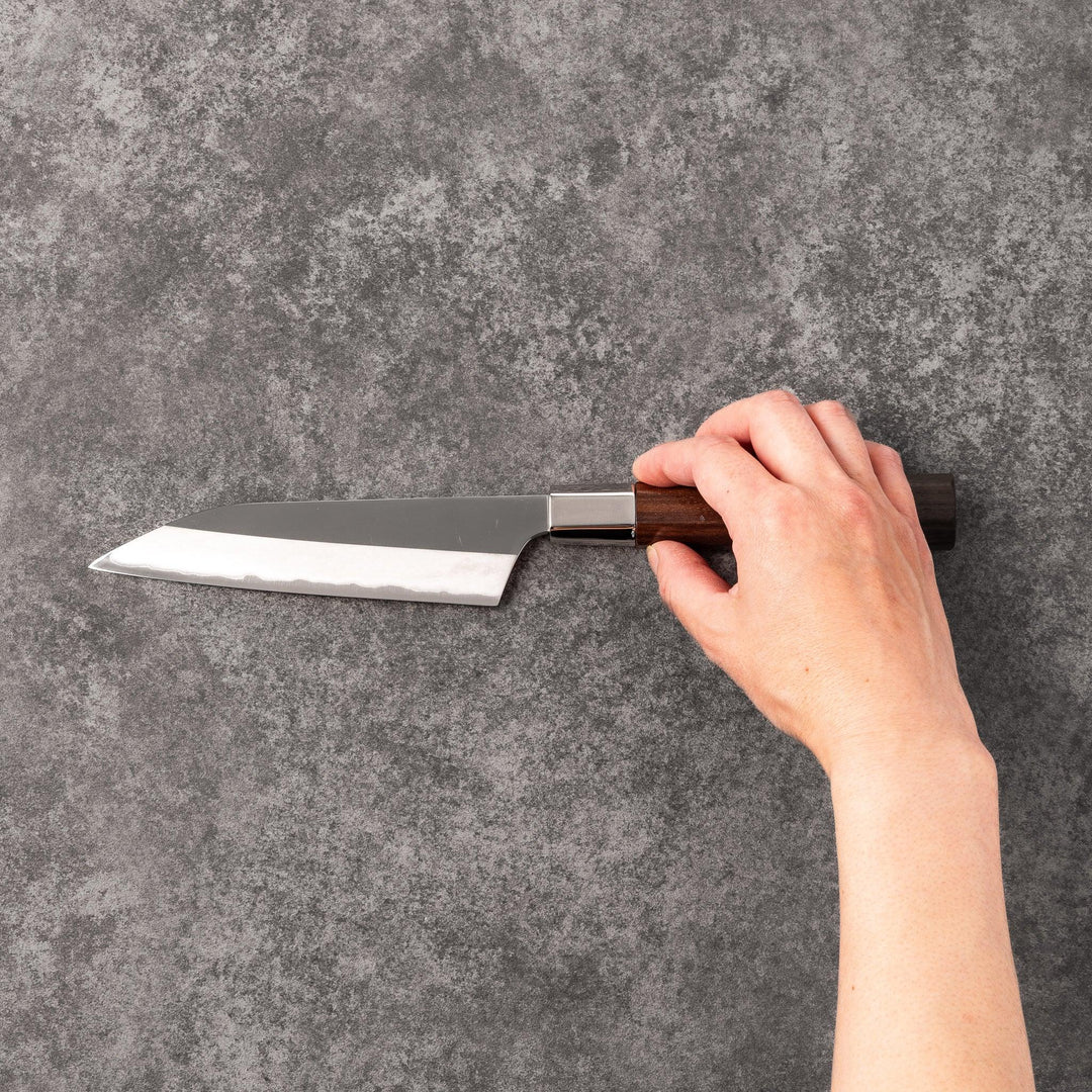 Petty knife with polished stainless steel blade and walnut wood handle for precise vegetable slicing and peeling.