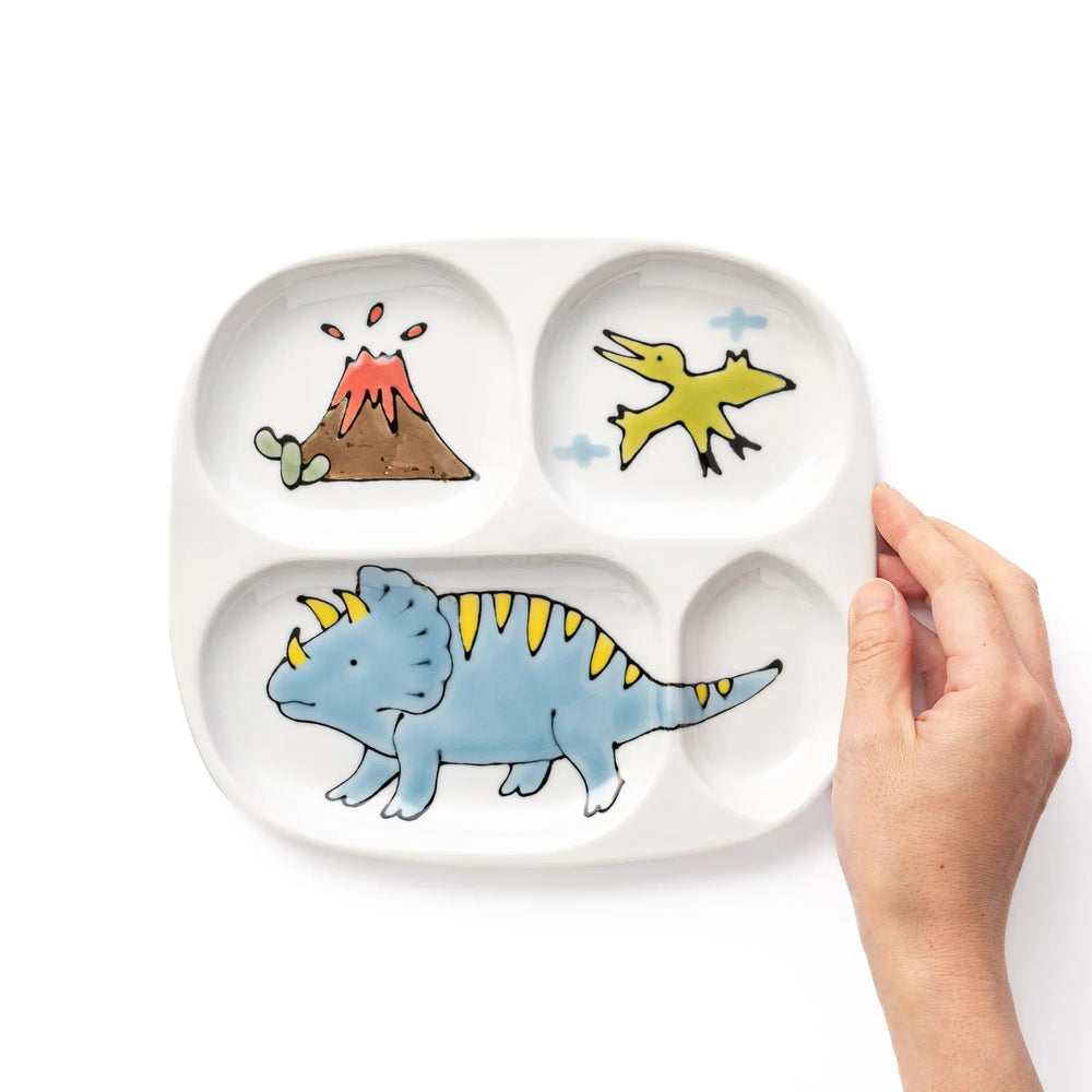 White ceramic kids divided plate with blue triceratops, yellow pterodactyl, red erupting volcano and blue cloud accents