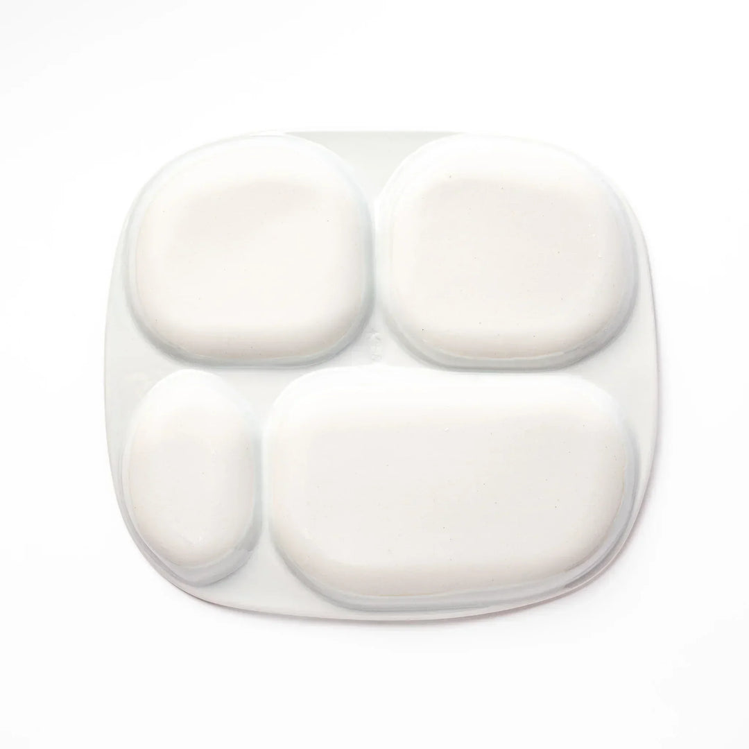 White ceramic kids divided plate with blue triceratops, yellow pterodactyl, red erupting volcano and blue cloud accents