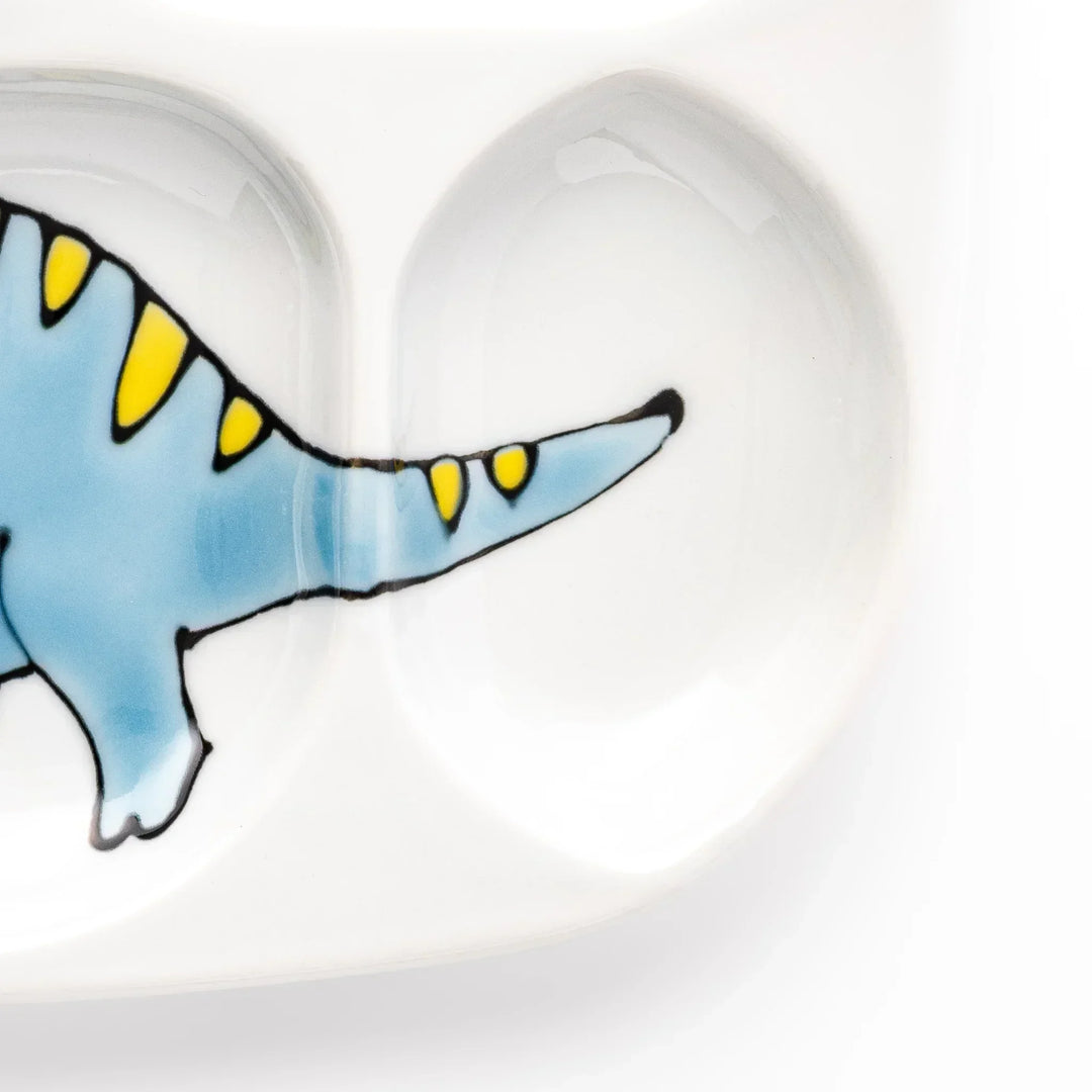 White ceramic kids divided plate with blue triceratops, yellow pterodactyl, red erupting volcano and blue cloud accents