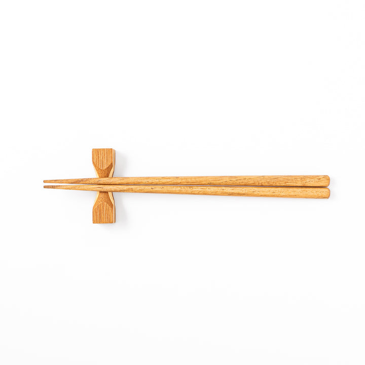 Japanese Tsuzumi bamboo chopstick rest with a hand carved hourglass shape and layered wood grain for dining tables