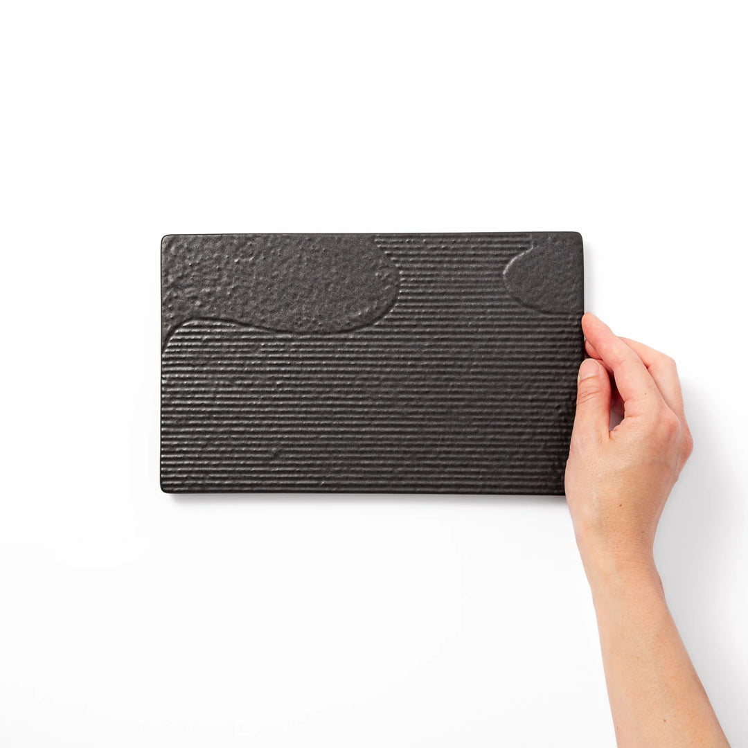 Black Japanese ceramic dinner plate with ridged woodgrain texture and matte gloss finish for modern dining.