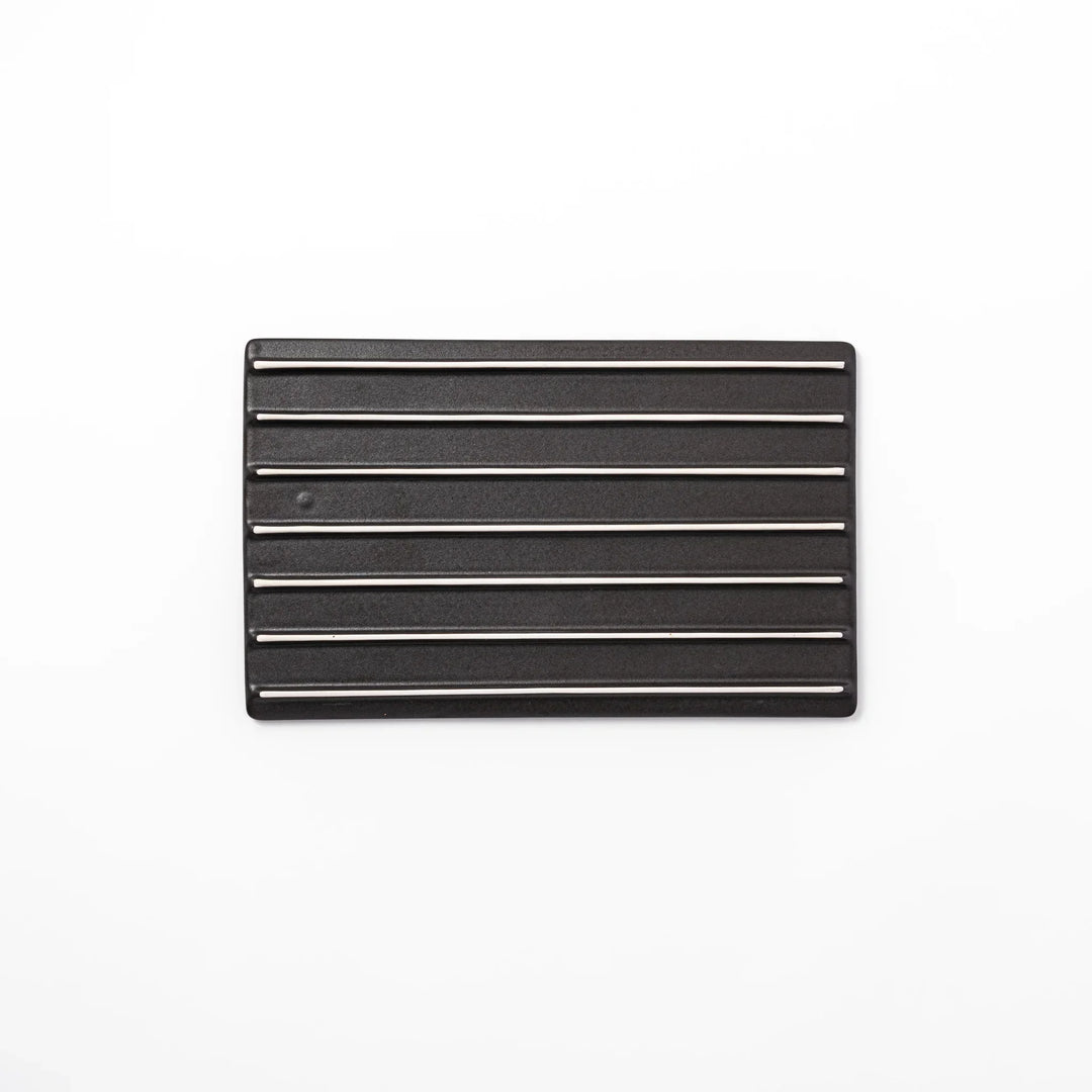 Black Japanese ceramic dinner plate with ridged woodgrain texture and matte gloss finish for modern dining.