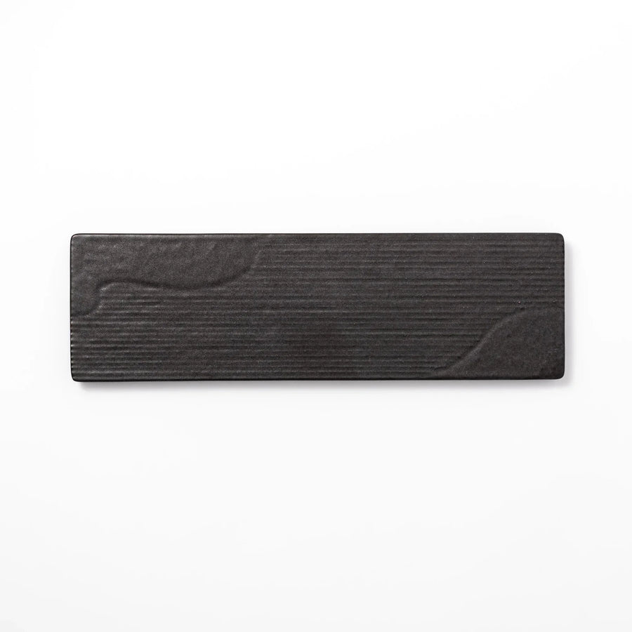 Rectangular black Japanese ceramic serving plate with subtle ridged woodgrain texture for modern dining.