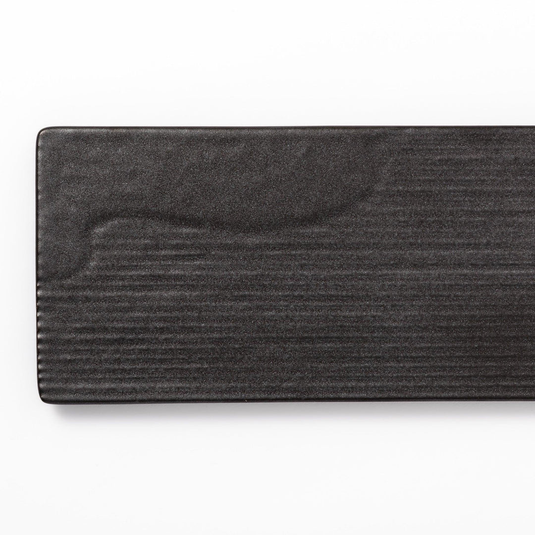 Rectangular black Japanese ceramic serving plate with subtle ridged woodgrain texture for modern dining.