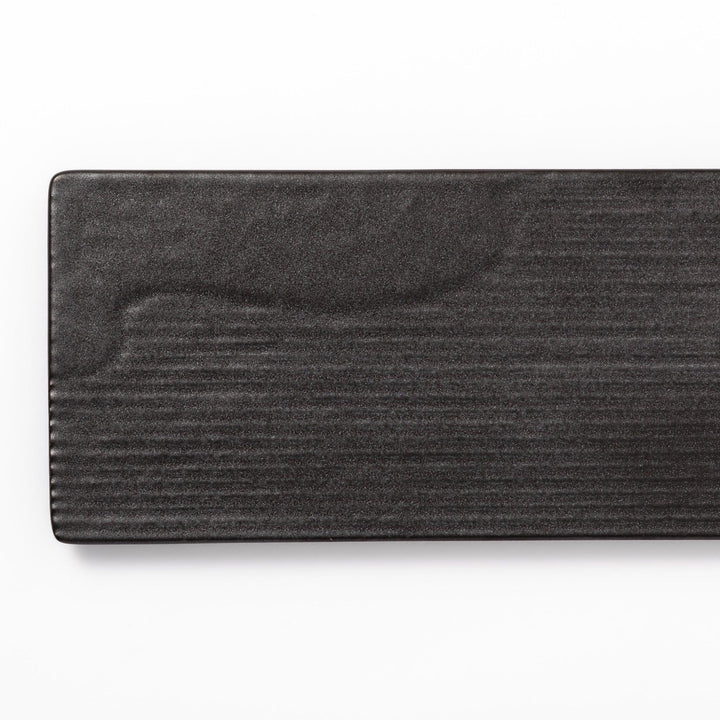 Rectangular black Japanese ceramic serving plate with subtle ridged woodgrain texture for modern dining.