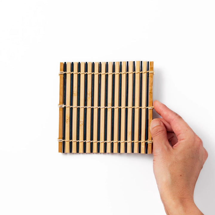Two tone bamboo coaster with dark and natural slats hand tied with twine for stylish Japanese settings.