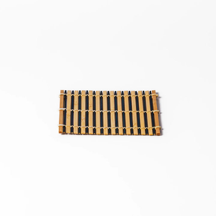 Two tone bamboo coaster with dark and natural slats hand tied with twine for stylish Japanese settings.