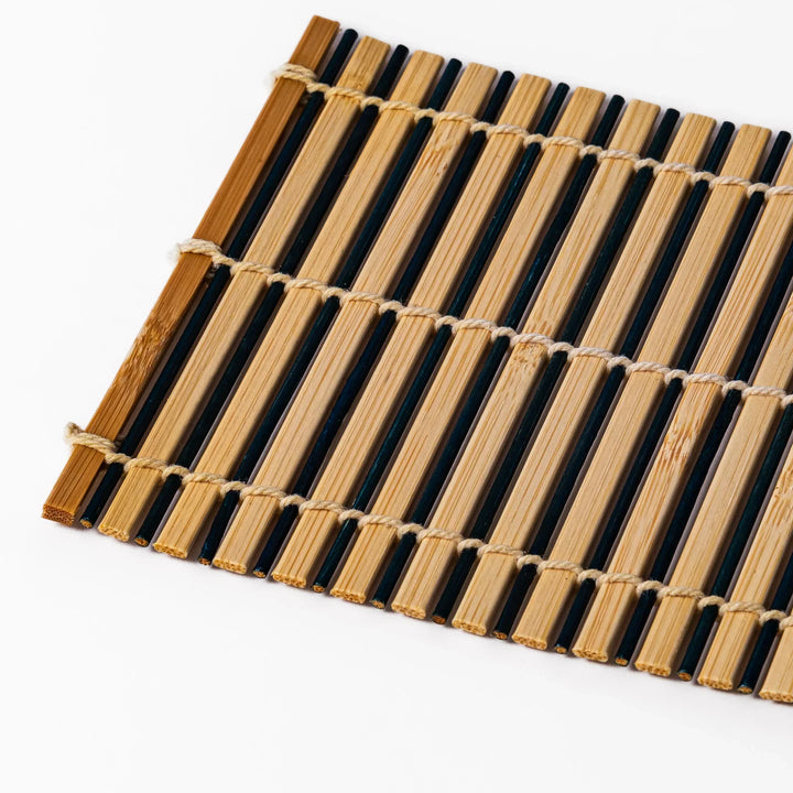 Two tone bamboo coaster with dark and natural slats hand tied with twine for stylish Japanese settings.