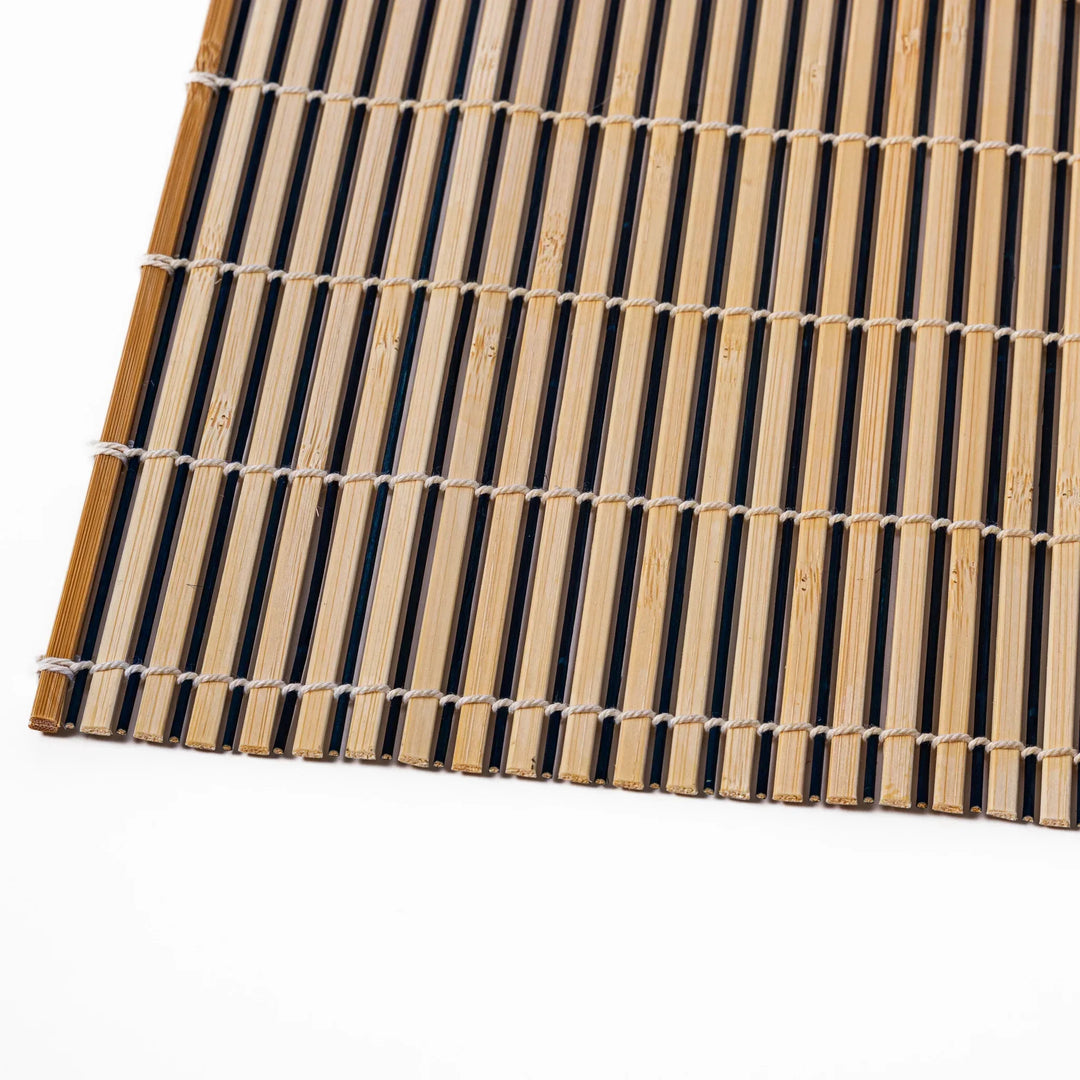 Two tone bamboo table mat with light and dark slats woven with white cord for textured Japanese dining.