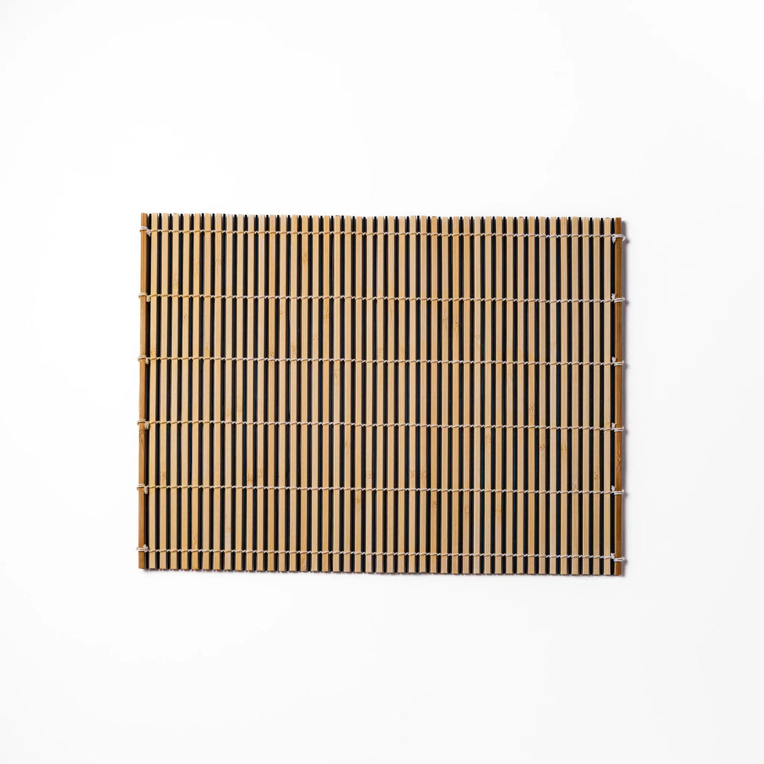 Two tone bamboo table mat with light and dark slats woven with white cord for textured Japanese dining.