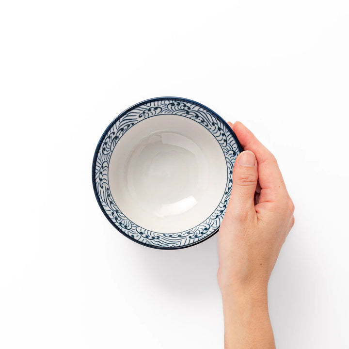 White porcelain rice bowl with navy blue wave ripple pattern and unglazed brown base, photographed on a white background.