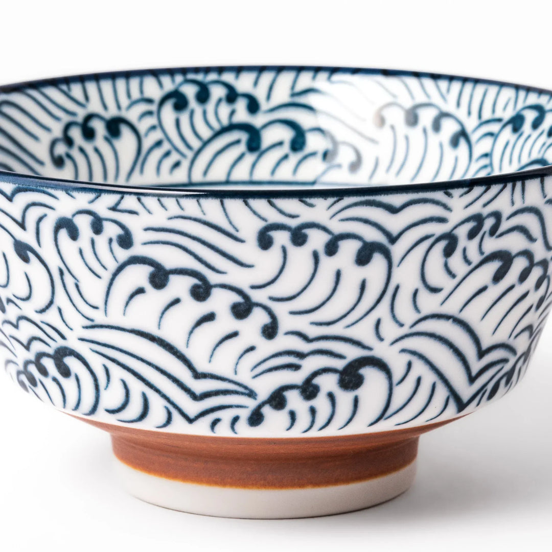 White porcelain rice bowl with navy blue wave ripple pattern and unglazed brown base, photographed on a white background.