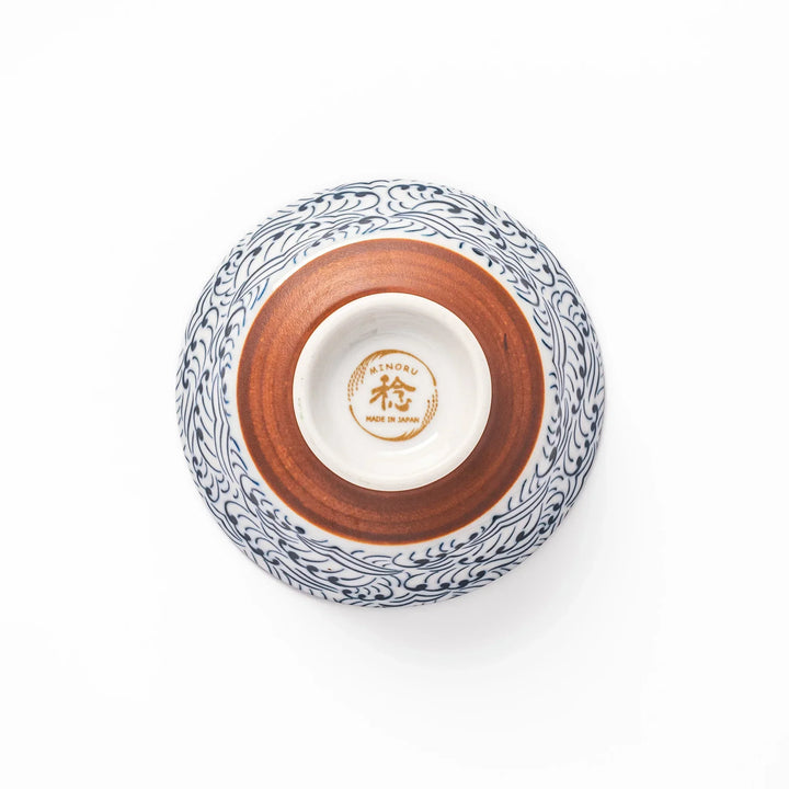 White porcelain rice bowl with navy blue wave ripple pattern and unglazed brown base, photographed on a white background.