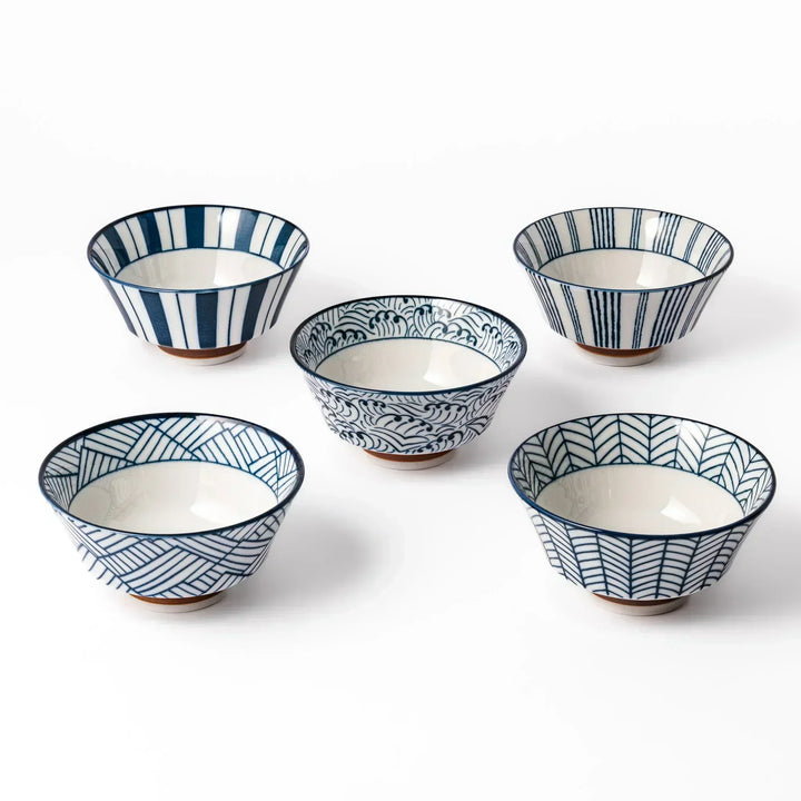 Fve Japanese rice bowls with blue geometric and wave patterns on white, arranged on a white surface.