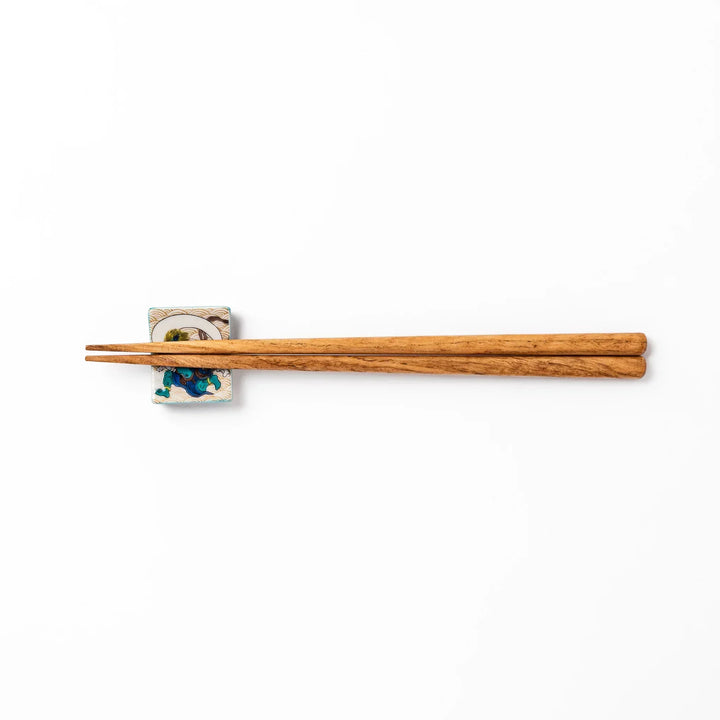 Japanese porcelain chopstick rest featuring the Wind God design with blue figure and gold wave pattern background.