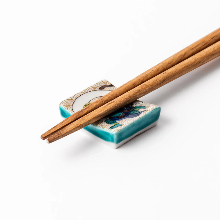 Japanese porcelain chopstick rest featuring the Wind God design with blue figure and gold wave pattern background.