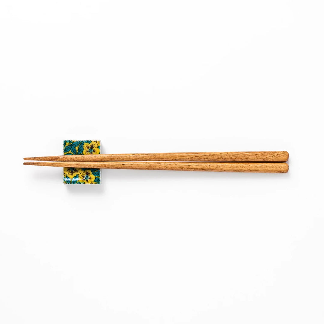 Rectangular Japanese ceramic chopstick rest with yellow floral design and teal leaves for elegant dining.