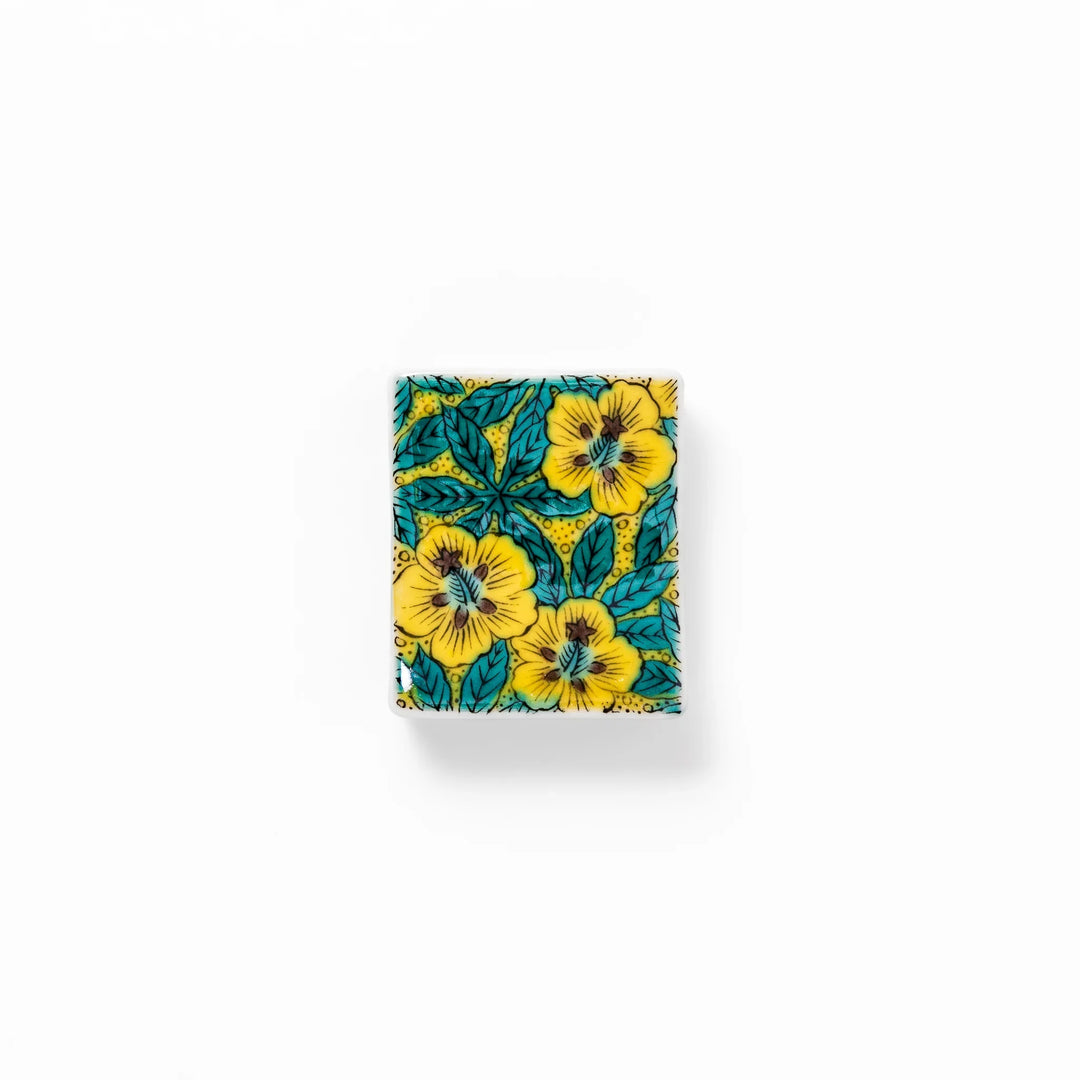Rectangular Japanese ceramic chopstick rest with yellow floral design and teal leaves for elegant dining.