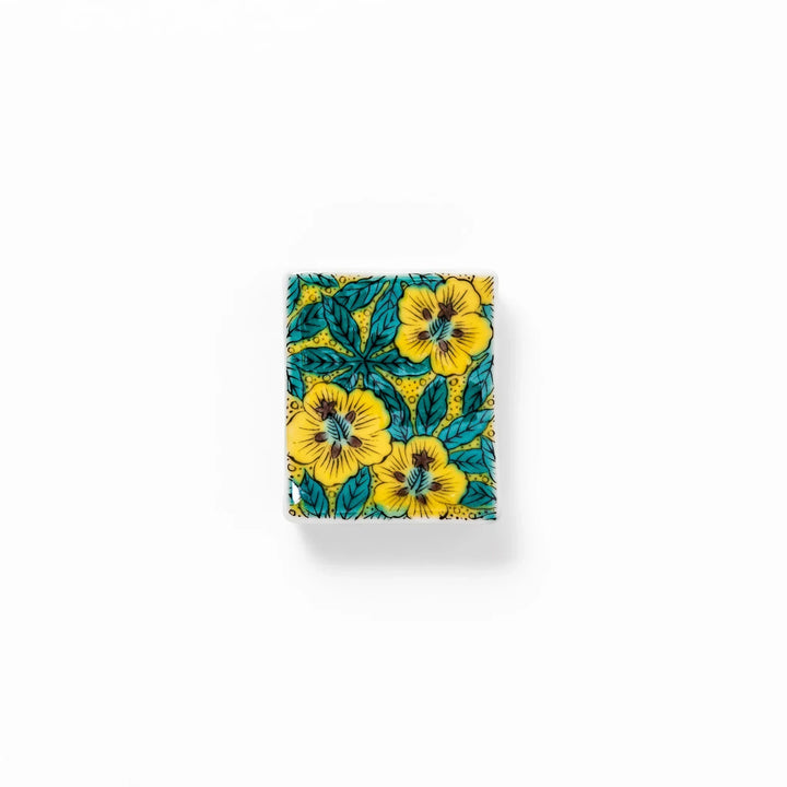 Rectangular Japanese ceramic chopstick rest with yellow floral design and teal leaves for elegant dining.