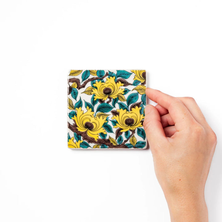 Square Japanese ceramic coaster with yellow peony flowers and teal leaves adding elegance to any table.