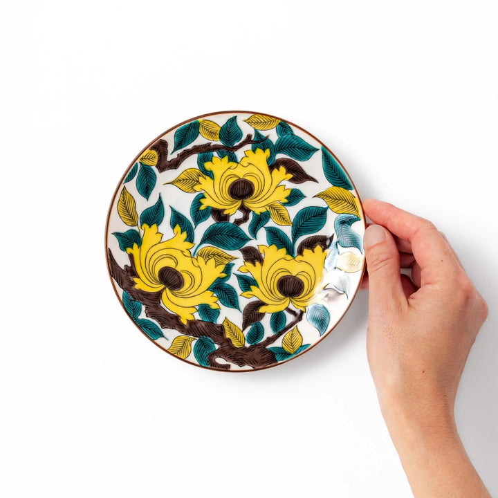 Japanese porcelain dessert plate with bold yellow peony blooms, green leaves, and brown branches on a white background