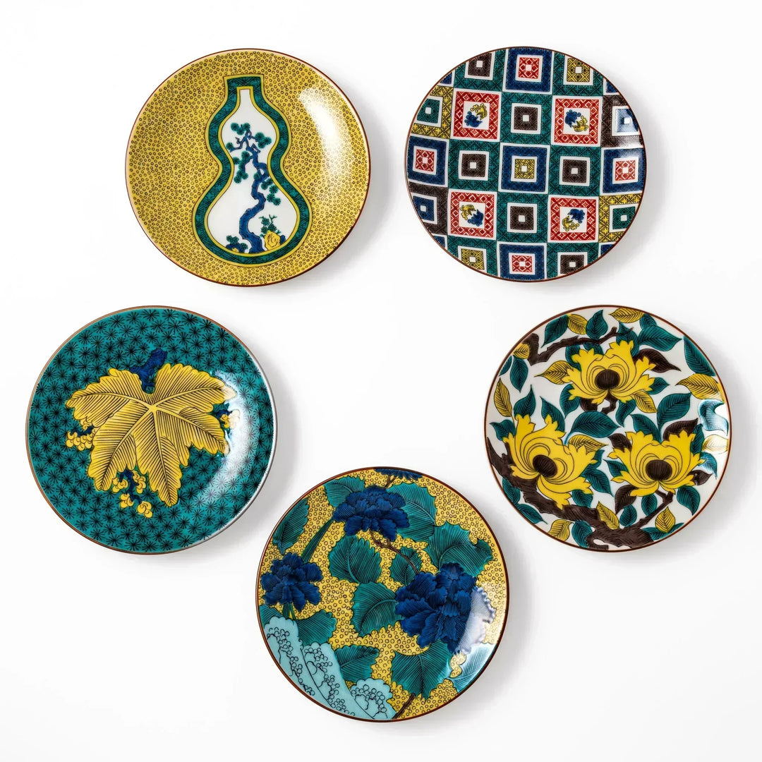 Set of Japanese porcelain dessert plates with bold yellow blue and green floral and geometric patterns.