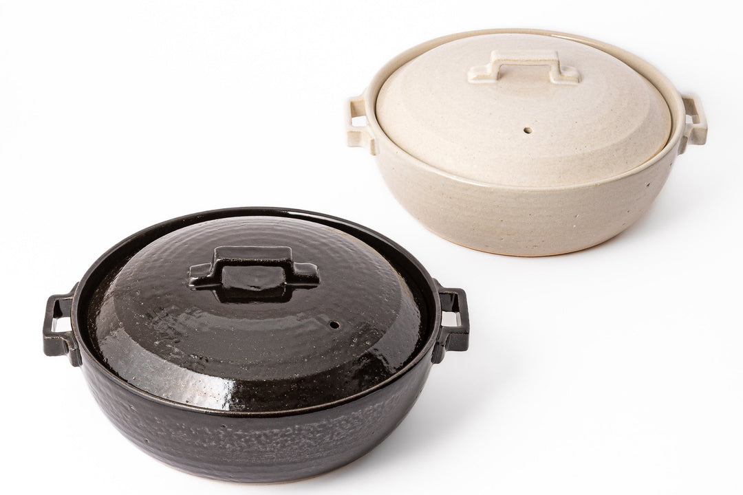 Black and white Japanese donabe set with vented lids and side handles featuring handcrafted ceramic texture