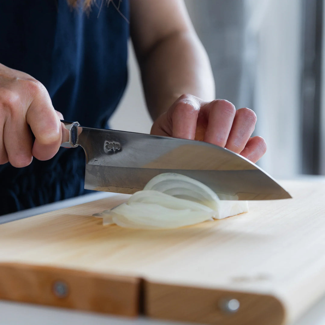 Tosa Ginsan Stainless Funayuki Knife cutting onion slices on a hinoki board, highlighting its smooth precision.