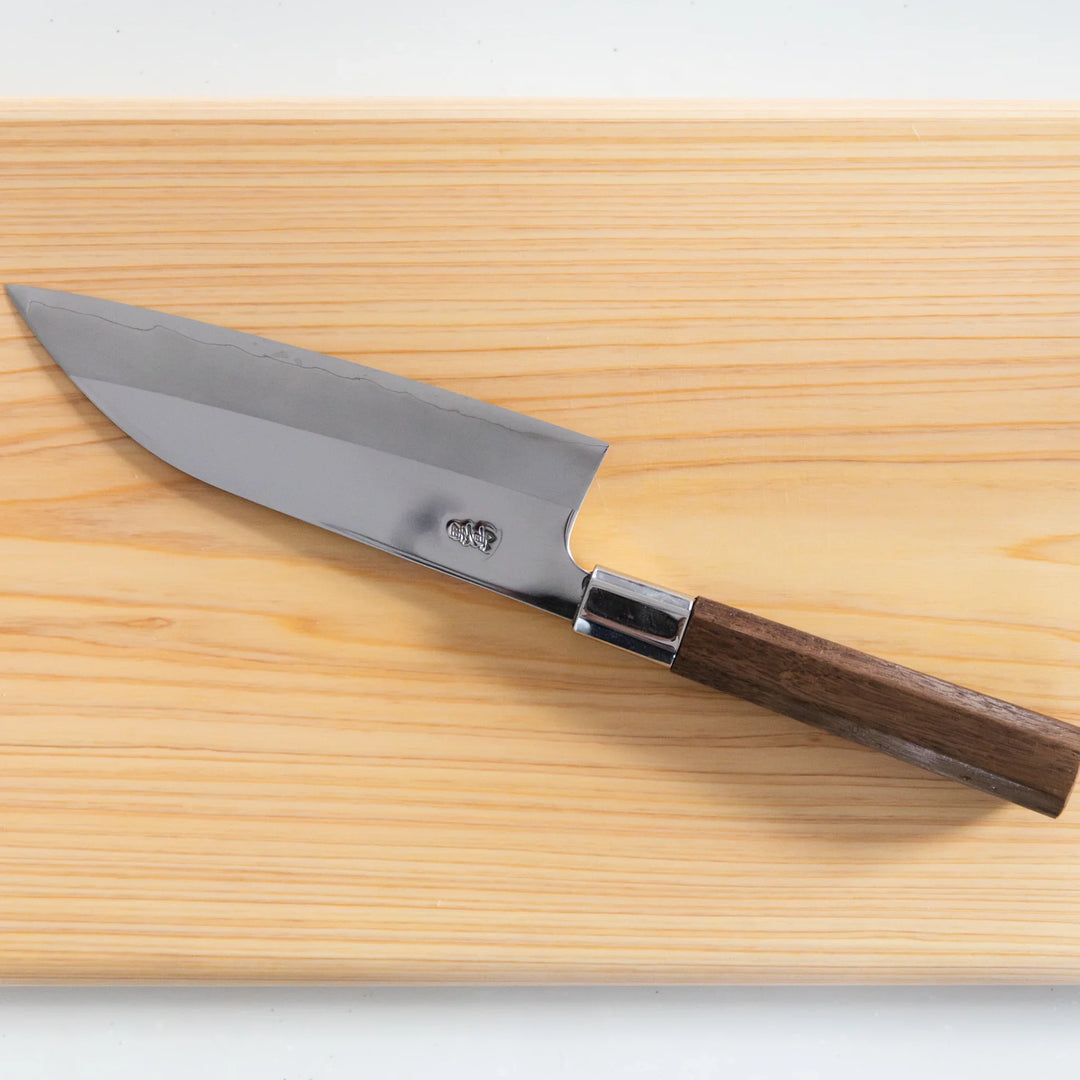 Tosa Ginsan Stainless Funayuki All-Purpose Knife resting on a hinoki cutting board, showcasing its elegant design.