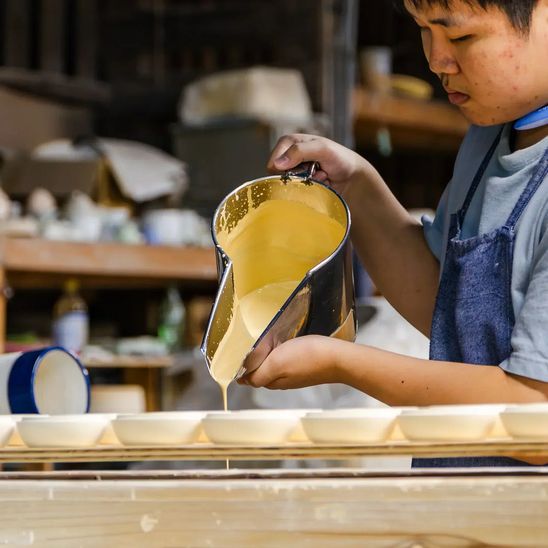 Artisan pouring slip into ceramic pieces for coating and shaping during pottery production in the workshop