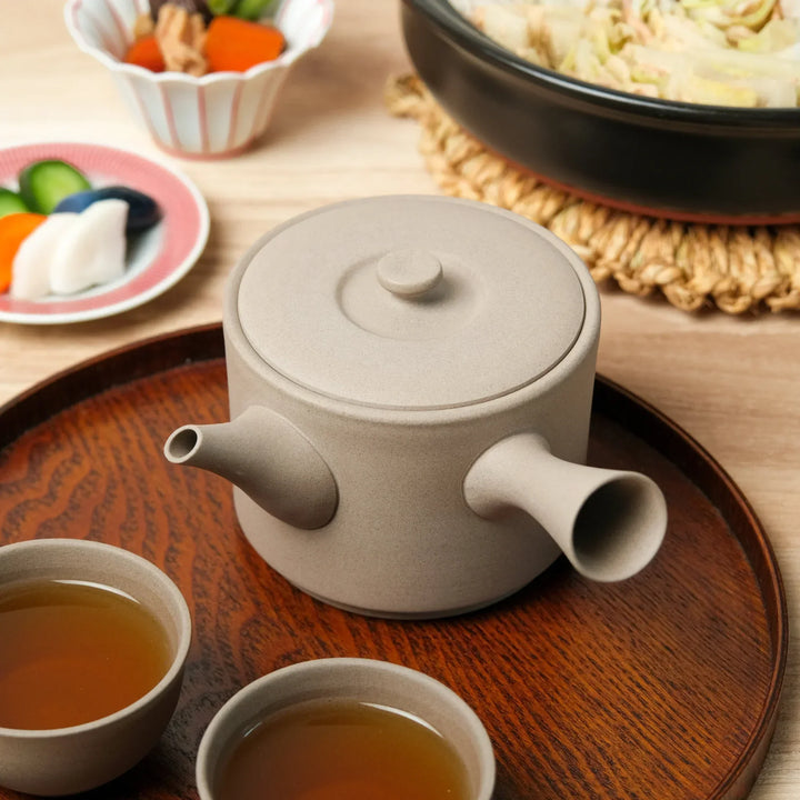 Large gray teapot with side handle displayed on wooden tray with cups perfect for Japanese tea.