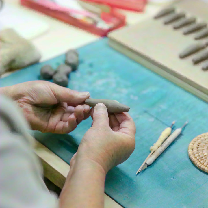 Artisan shaping a small piece of clay by hand during the early forming stage of ceramic production