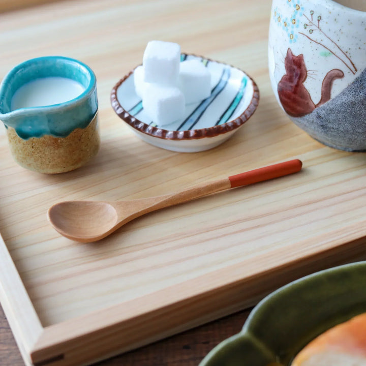 Minimalist beech wood spoon with slender handle tipped in pastel orange, ideal for scooping tea or sugar with elegance.