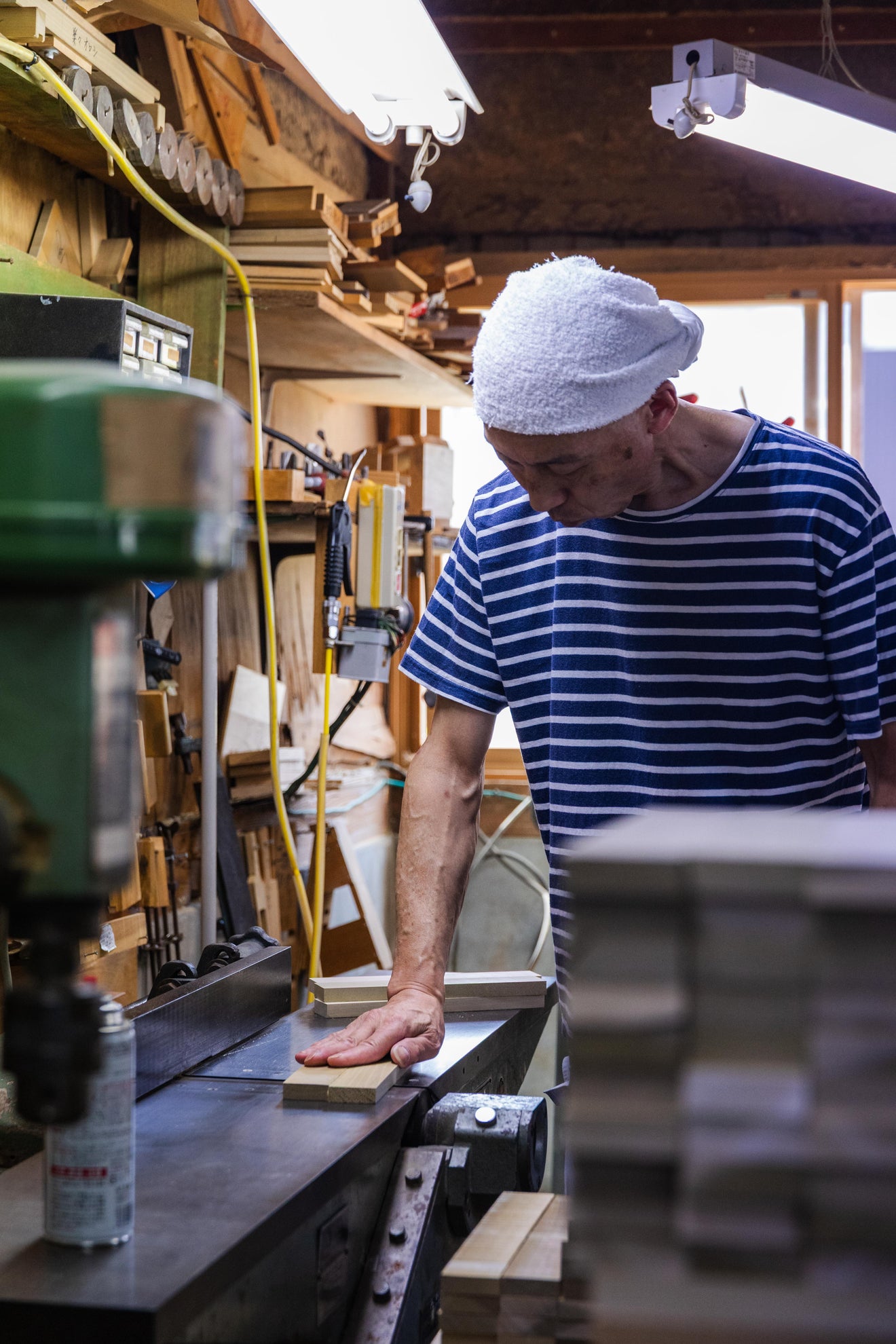 Japanese woodworker crafting wooden handle for Oyanagi peeler in a traditional woodworking workshop
