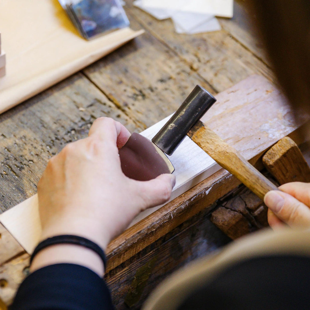 Wood artisan shaping a hinoki piece by hand with a mallet in a traditional workshop