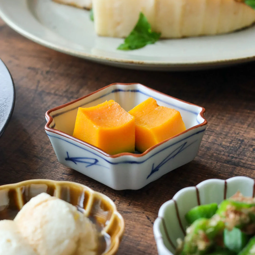 A diamond-shaped porcelain Japanese condiment bowl with pine needle design, serving simmered kabocha.
