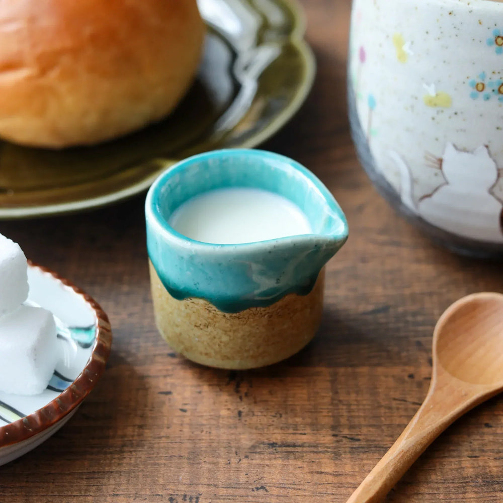 Turquoise sauce pourer with a smooth glaze and textured base, perfect for serving sauces or dressings.