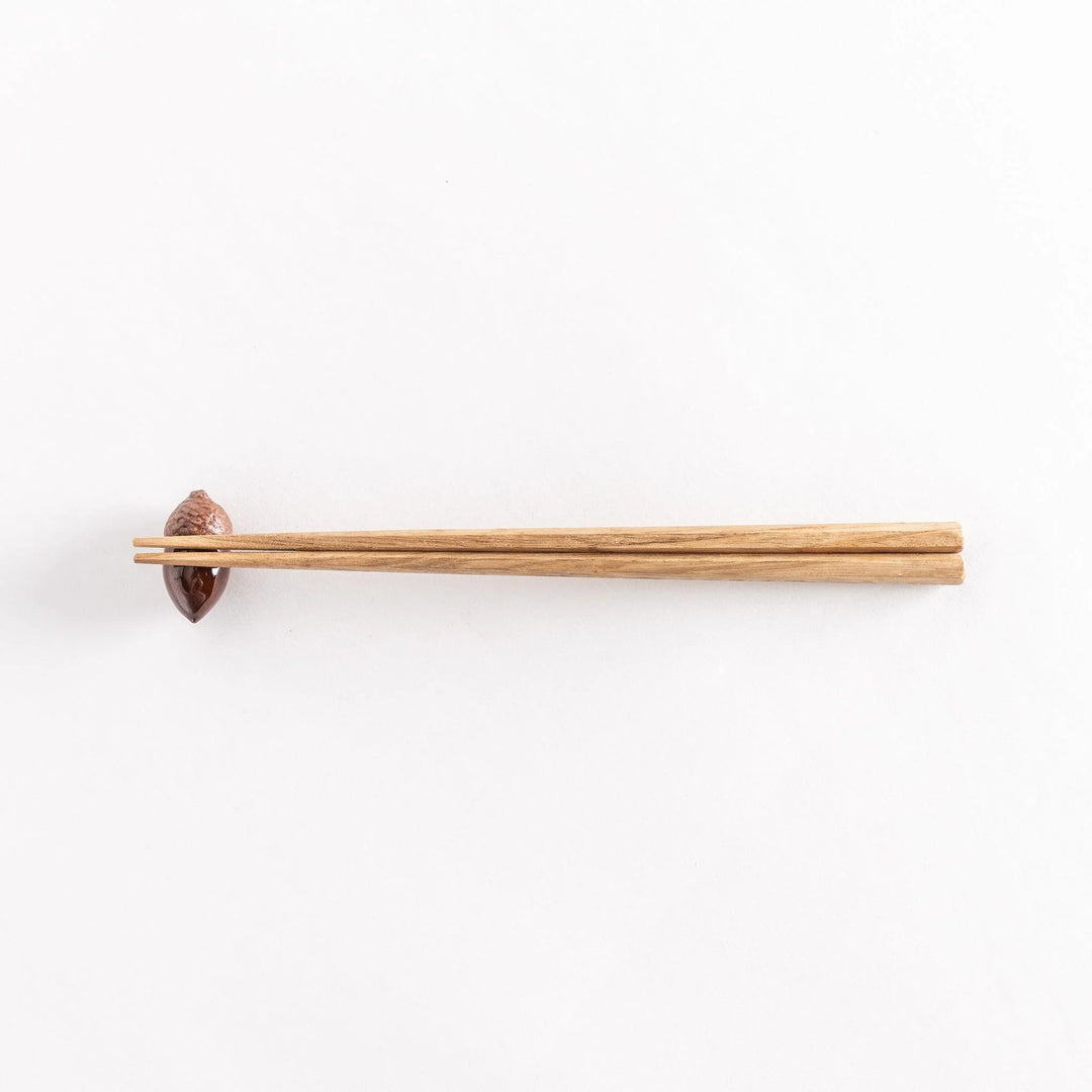 Acorn shaped ceramic chopstick rest with glossy brown finish adding natural warm touch to table.