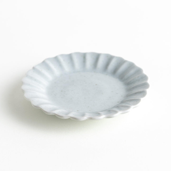 A small white ceramic plate with a fluted edge, featuring a clean, simple design.