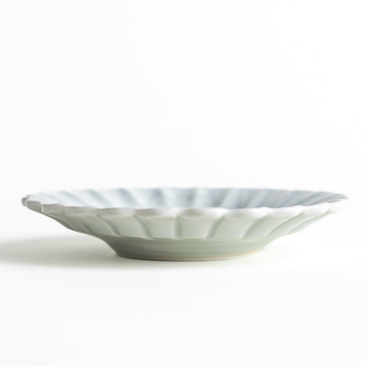 A small white ceramic plate with a fluted edge, featuring a clean, simple design.