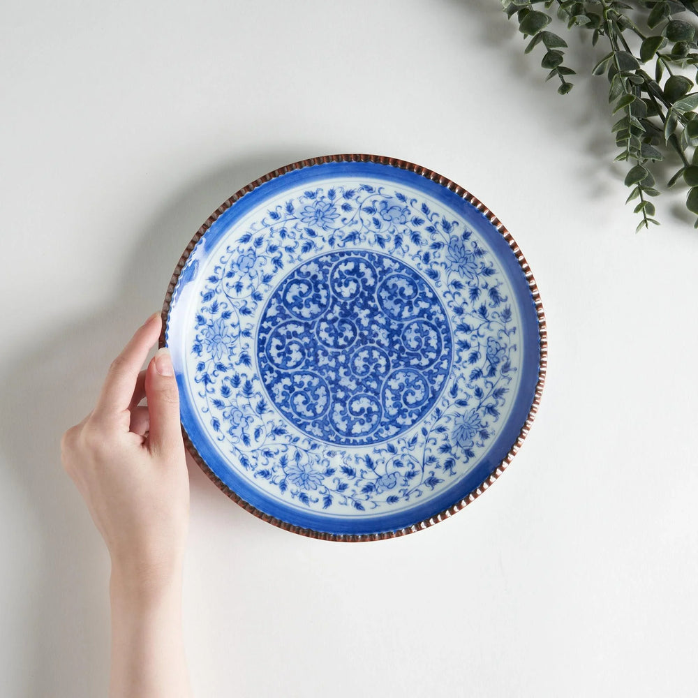 Ceramic plate with intricate blue floral design and bold circular motif framed by copper textured rim.