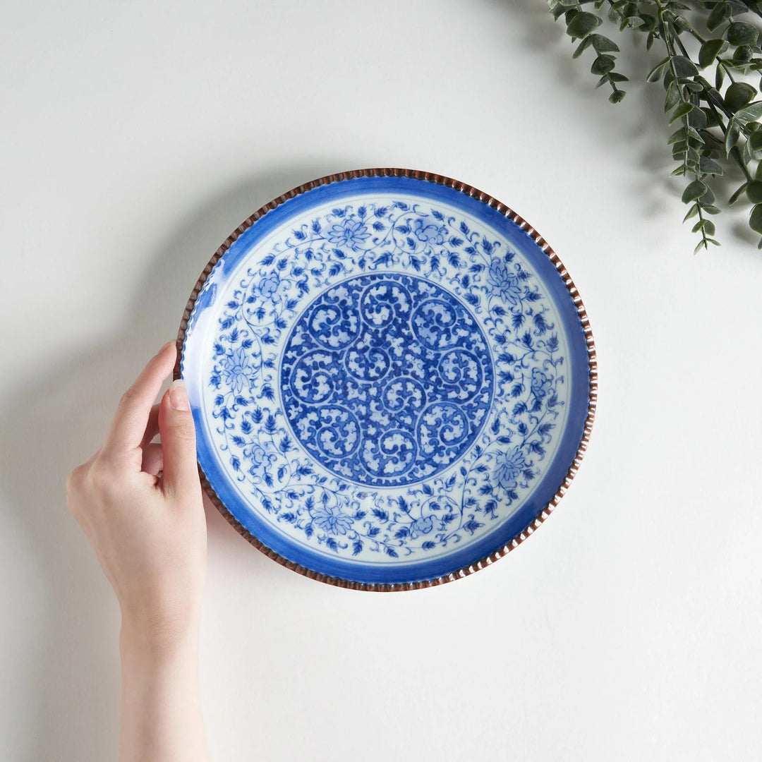 Ceramic plate with intricate blue floral design and bold circular motif framed by copper textured rim.