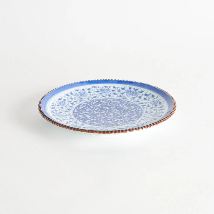 Ceramic plate with intricate blue floral design and bold circular motif framed by copper textured rim.