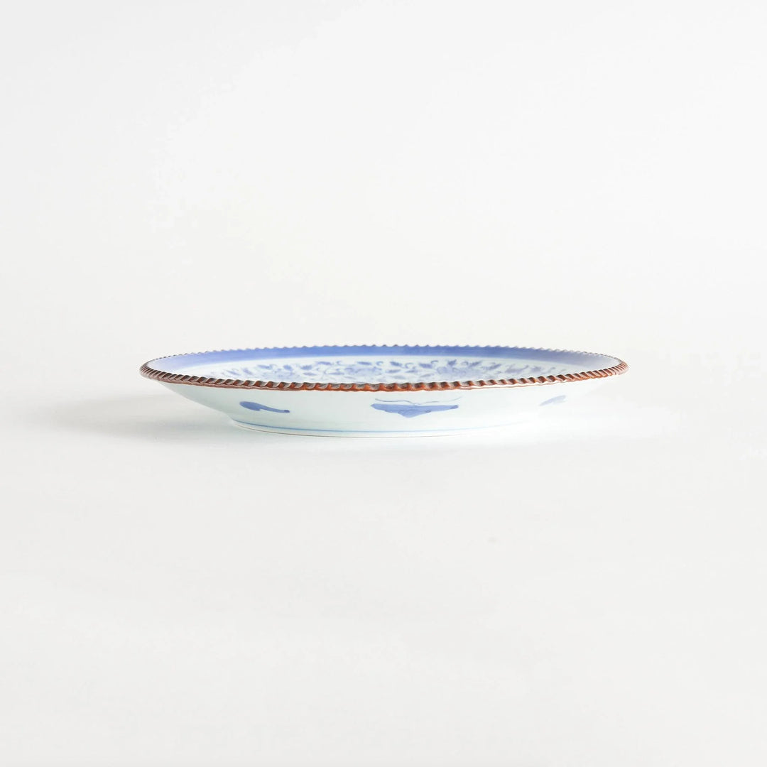 Ceramic plate with intricate blue floral design and bold circular motif framed by copper textured rim.