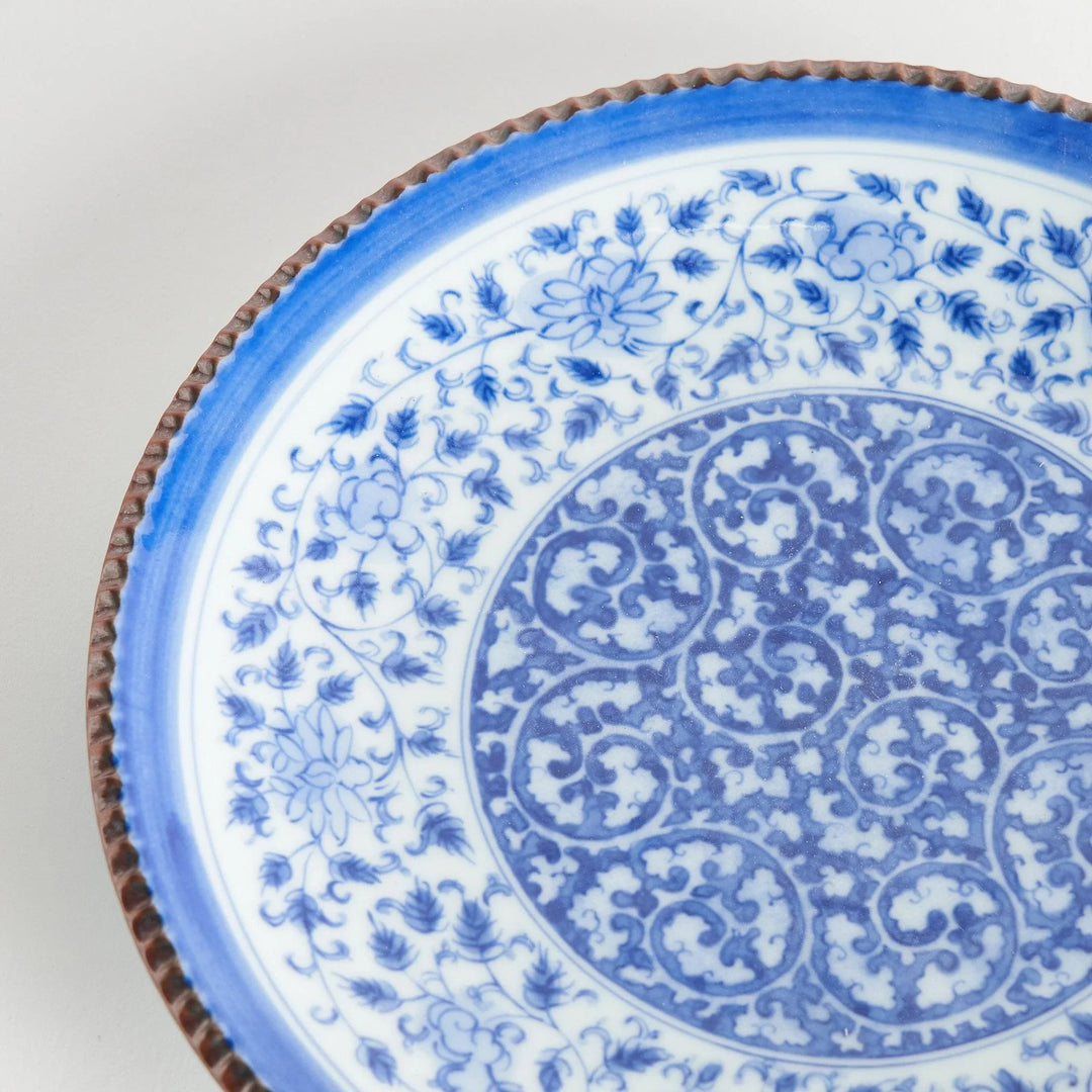 Ceramic plate with intricate blue floral design and bold circular motif framed by copper textured rim.