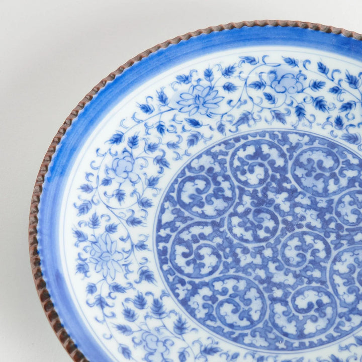 Ceramic plate with intricate blue floral design and bold circular motif framed by copper textured rim.