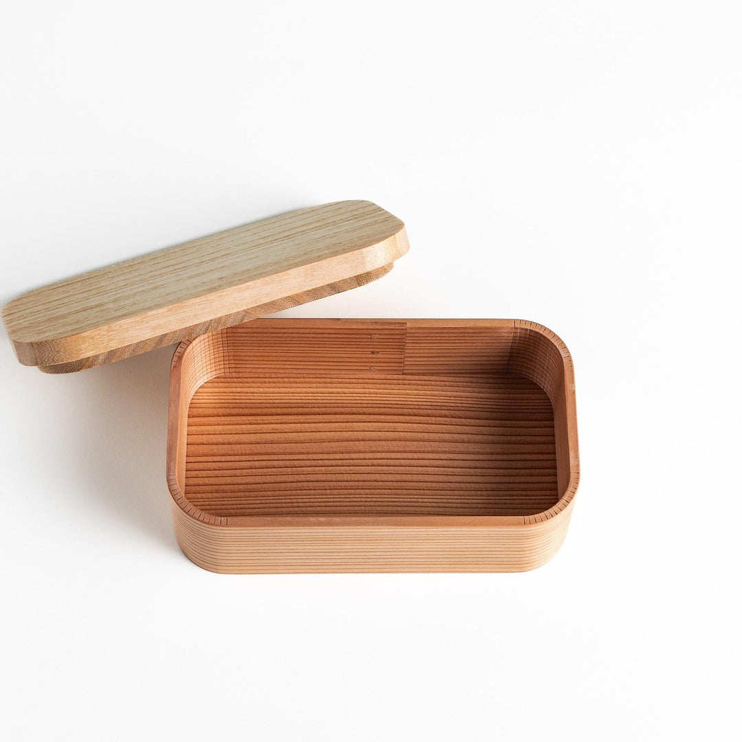 Cedar bento box with lid showing natural wood grain and rounded edges for minimalist Japanese look.